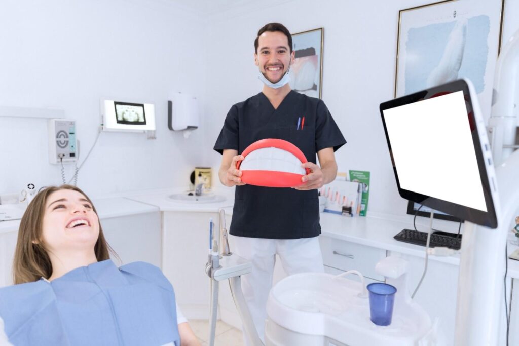 Dentist showing a dental model to a patient in a clinic.